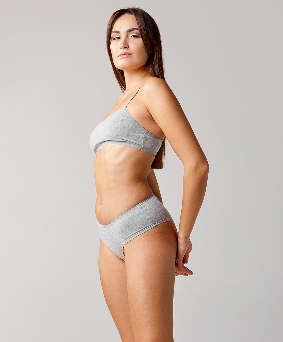 Model in gray lingerie against plain background.