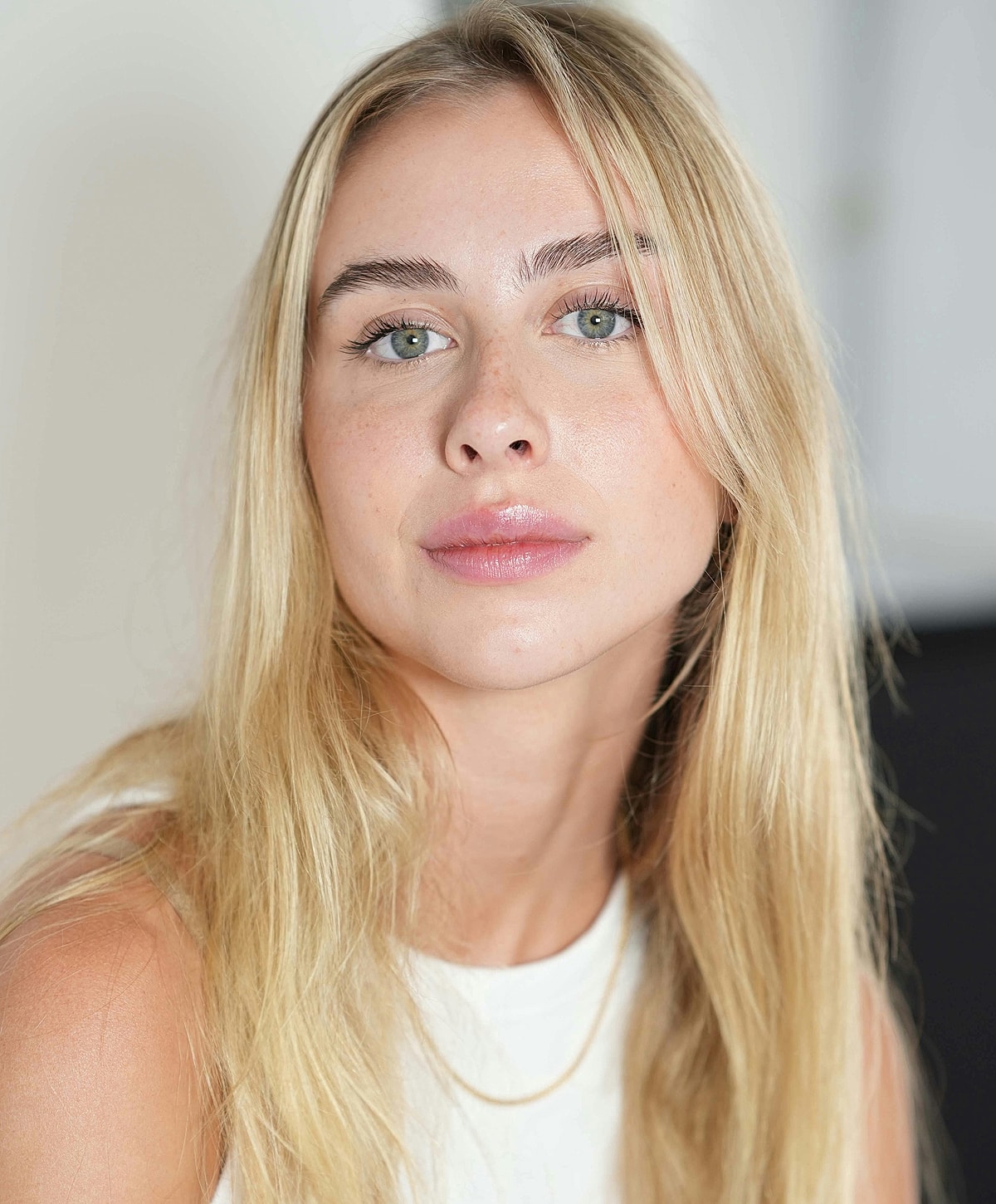 Smiling woman in white lingerie on light background.
