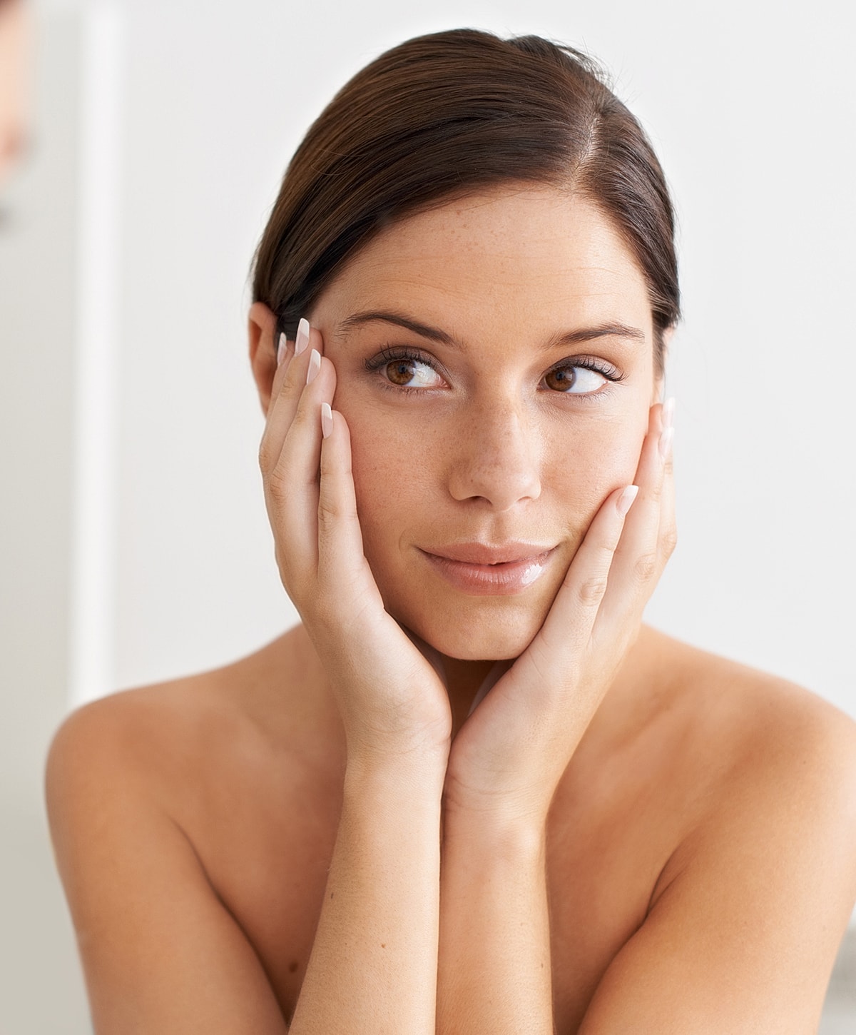 Smiling woman in white lingerie on light background.
