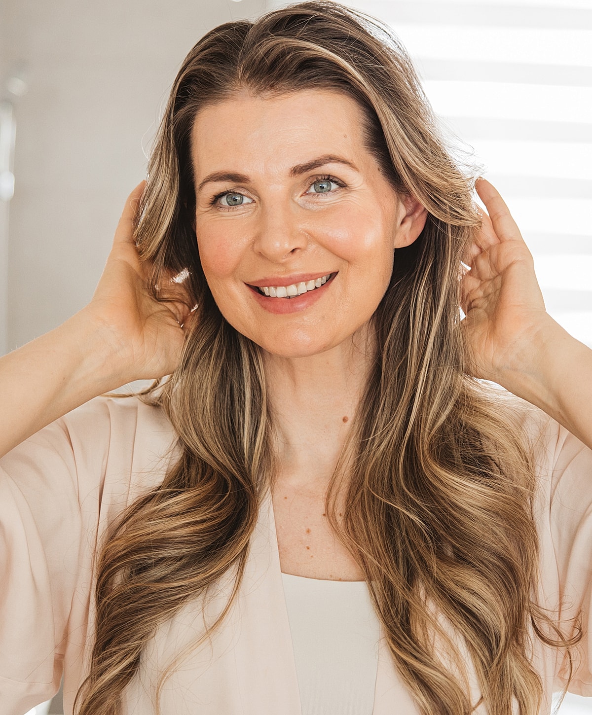 Smiling woman with long, wavy hair indoors.