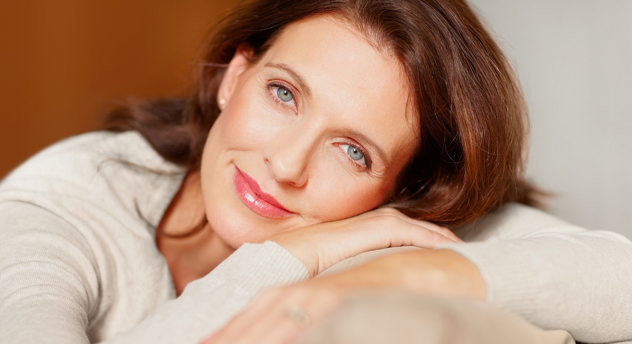 Smiling woman resting her chin on her hands.