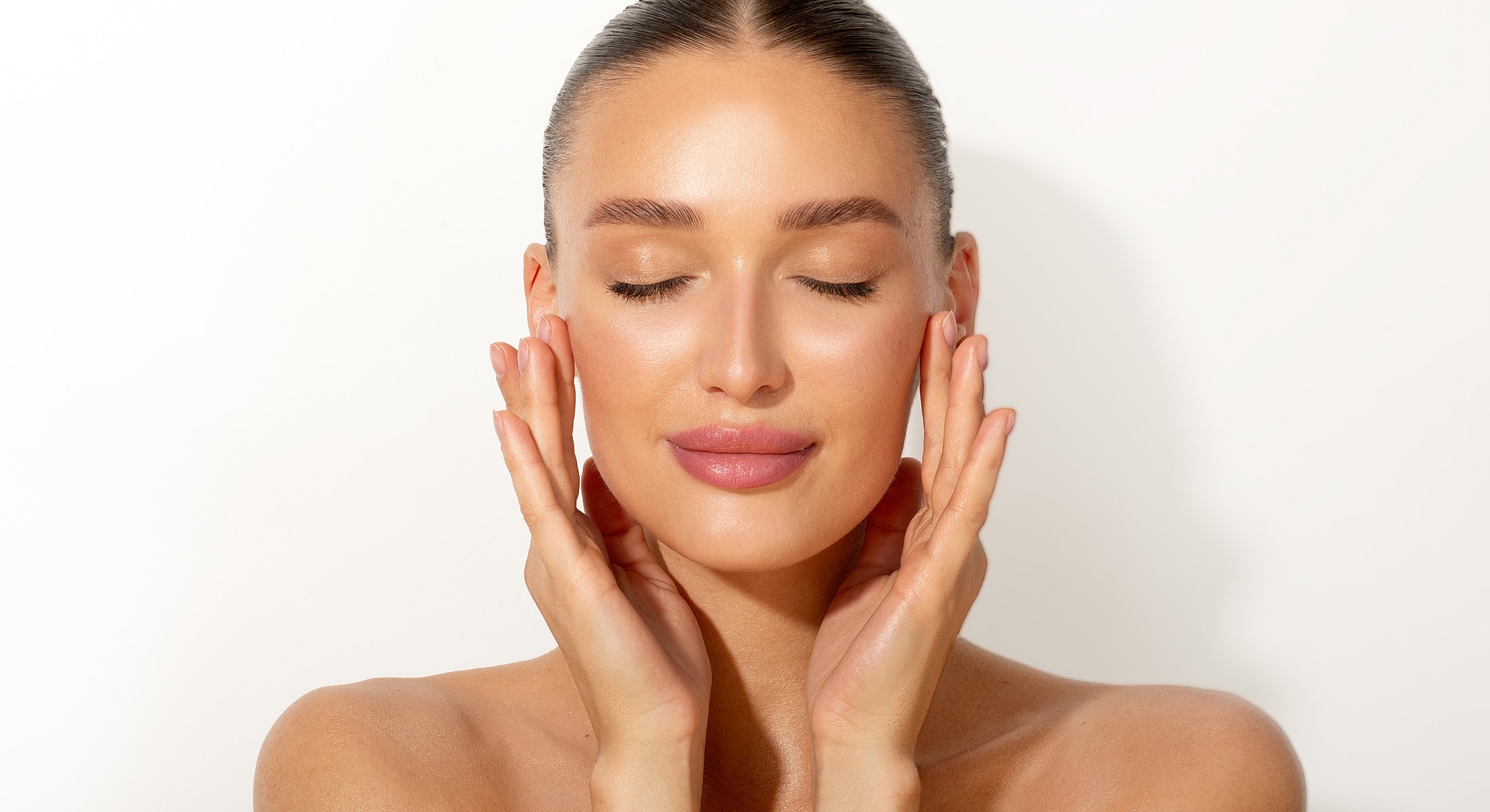 Woman with hands on face, eyes closed.